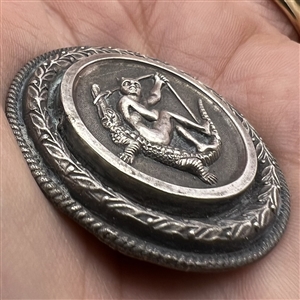 French white metal button of the devil sitting on an alligator.