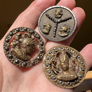 Three brass buttons of famous people’s heads.