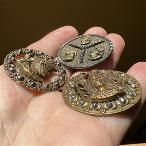 Three brass buttons of famous people’s heads.