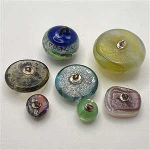Seven assorted glass studio paperweight buttons.