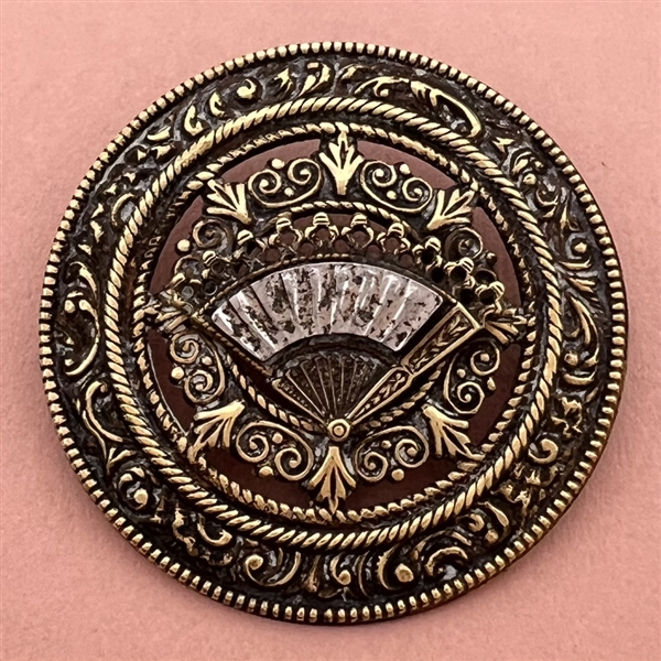Ornate brass open work button with steel fan.