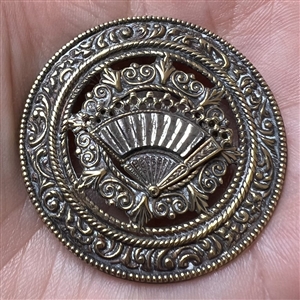 Ornate brass open work button with steel fan.