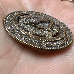 Ornate brass open work button with steel fan.