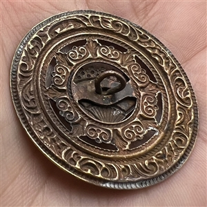 Ornate brass open work button with steel fan.