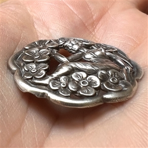 Hallmarked silver button of woman among flowers.
