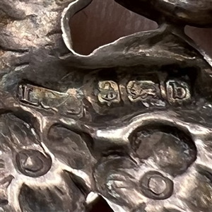 Hallmarked silver button of woman among flowers.