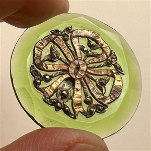 Transparent green glass button with bow.