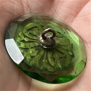 Transparent green glass button with bow.