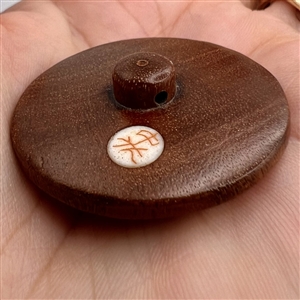 Natural material set in boxwood button of a frog.