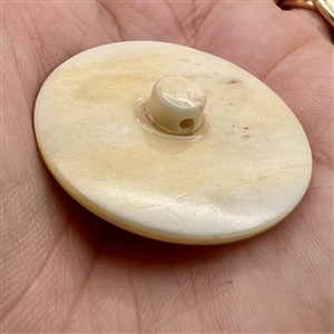 Child playing a drum natural material button.
