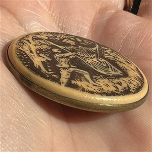 Large ivoroid “tight top” button of a man pushing a woman on a swing.