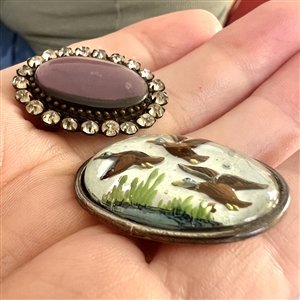 Two oval glass in metal buttons.