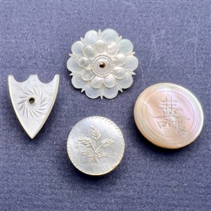 Four assorted incised pearl and shell buttons.