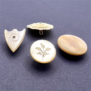 Four assorted incised pearl and shell buttons.