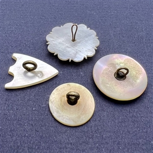Four assorted incised pearl and shell buttons.