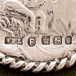 Hallmarked silver button of man playing an instrument in a garden.