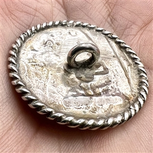 Hallmarked silver button of man playing an instrument in a garden.