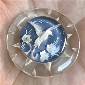 Reverse carved and painted acrylic button of a flying bird.