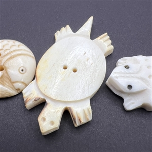 Three carved natural material buttons of animals.
