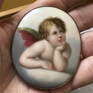 Extra large oval porcelain button of a cherub contemplating.