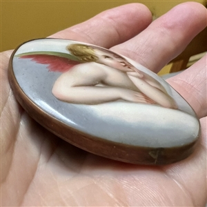 Extra large oval porcelain button of a cherub contemplating.