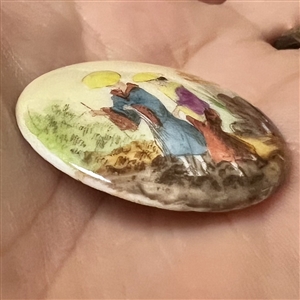 Glazed porcelain button of two Asian woman in garden setting.