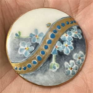 Painted porcelain button of forget-me-not flowers.