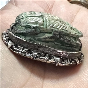 Ceramic button of an Egyptian scarab design set in metal.