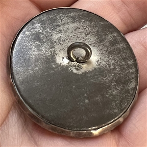 Silvered brass button of a cherub with flowers.