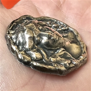 White metal button of a woman’s head with grapes.