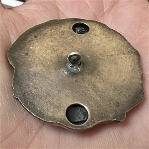 White metal button of a woman’s head with grapes.