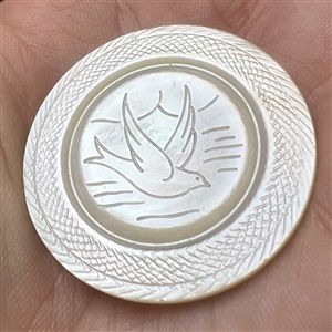 Incised pearl button of a bird flying over water.