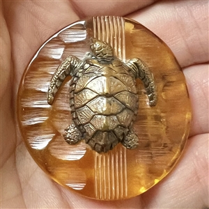 Brass sea turtle over apple juice Bakelite button.