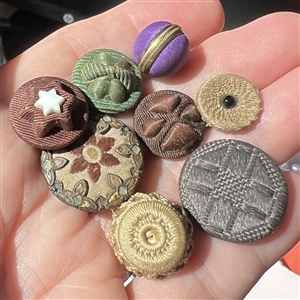 Eight assorted fabric buttons.
