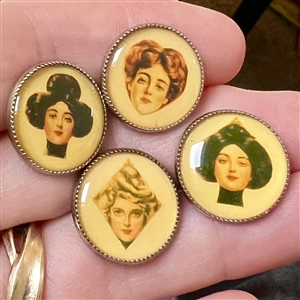 Set of four paper under celluloid sheet (?) set in metal buttons.