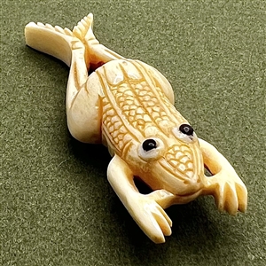 Carved natural material button of a frog.