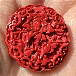 Modern “cinnabar” button of plant life over a background of squares.