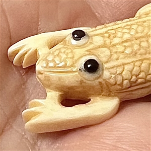 Carved natural material button of a frog.