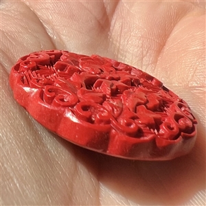 Modern “cinnabar” button of plant life over a background of squares.