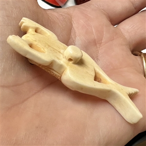Carved natural material button of a frog.
