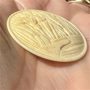 Carved natural material button of Japanese Iris among leaves.  