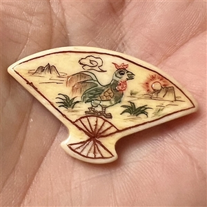 Carved natural material button of a fan decorated with a rooster.