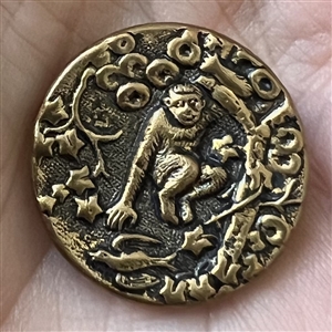 Brass button of a monkey in a tree.