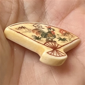 Carved natural material button of a fan decorated with a rooster.