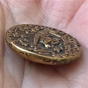 Brass button of a monkey in a tree.