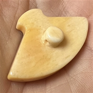 Carved natural material button of a fan decorated with a rooster.