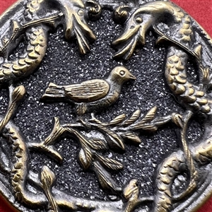 Brass button with galena of a bird surrounded by two snakes.