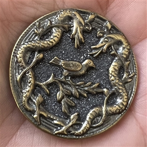 Brass button with galena of a bird surrounded by two snakes.