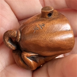 Boxwood button of tiny frog on poppy pod.