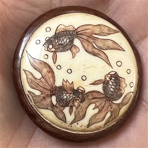 Carved material in wood button of a three koi swimming.